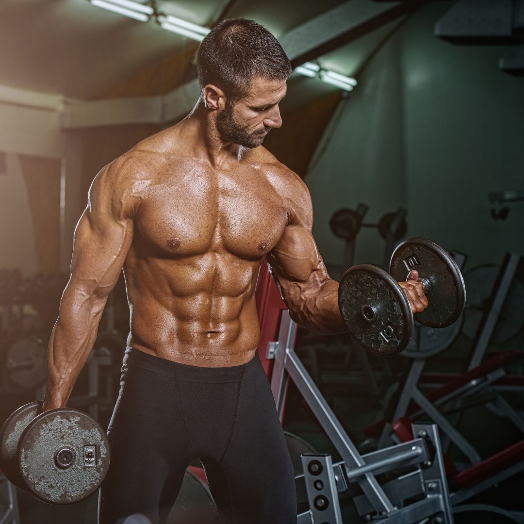 Hombre musculoso realizando ejercicios con pesas en el gimnasio, mostrando fuerza y definición muscular.