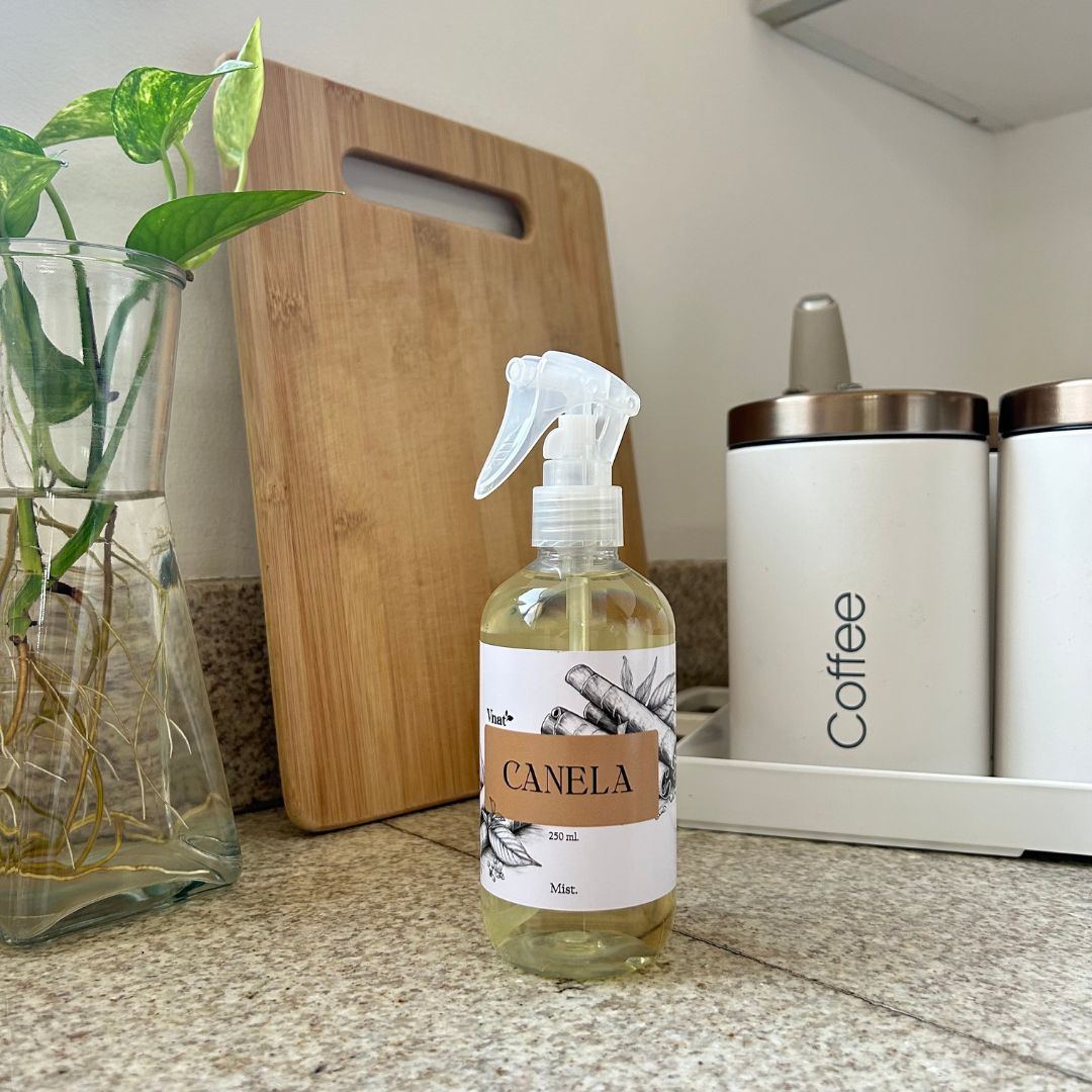 Mist aromatizante de canela de 250ml en una cocina junto a un jarrón con plantas y un recipiente de café.