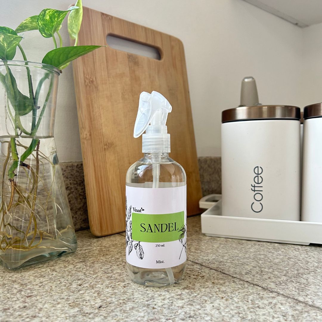 Mist aromatizante de sandel de 250ml en una cocina junto a un jarrón con plantas y un recipiente de café.