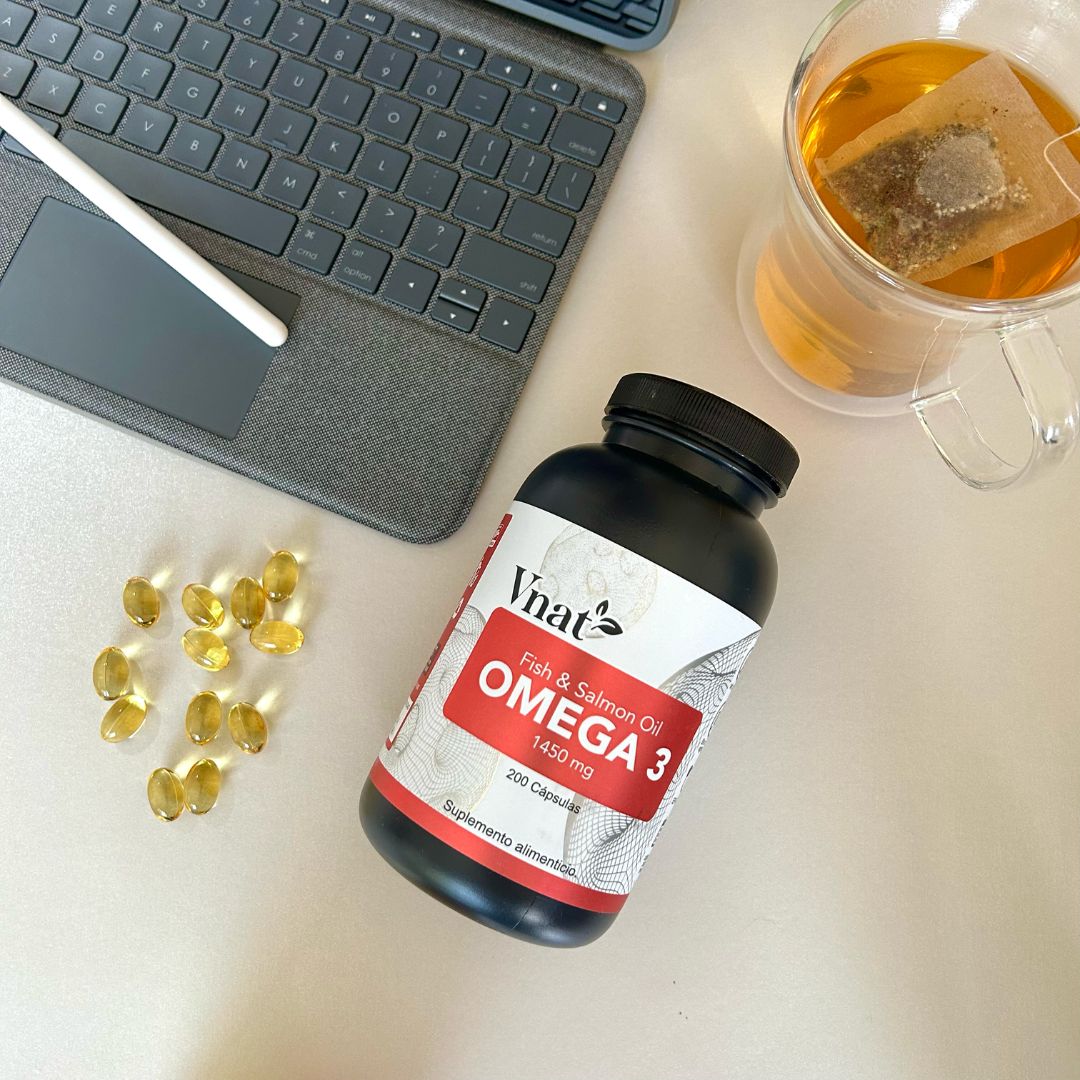 Bote de Omega 3 Fish and Salmon Oil 1450mg con 200 cápsulas de Vnat al lado de una laptop Apple y una taza de té