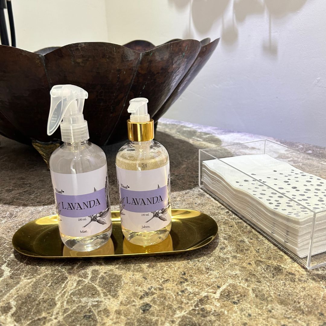 Kit de mist y jabón de lavanda de Vnat, frascos de 250 ml sobre una bandeja dorada en un baño elegante con un lavabo de diseño único y servilletas al fondo.